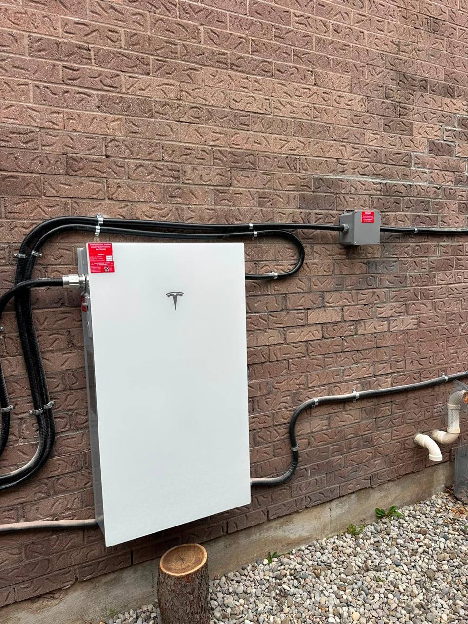 Tesla Powerwall battery installed on a brick wall